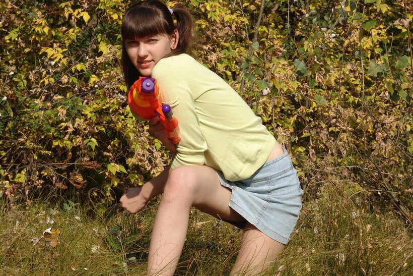 Photo 4 — Outdoors, a playful teen undresses fully and shows her bare pussy close-up