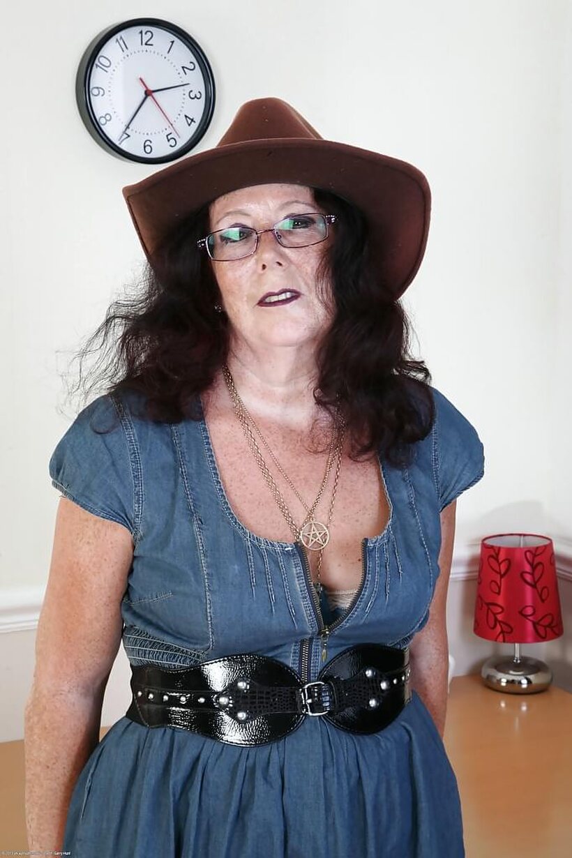 Photo 1 — Clothed Zadi poses with her big tits on display in boots