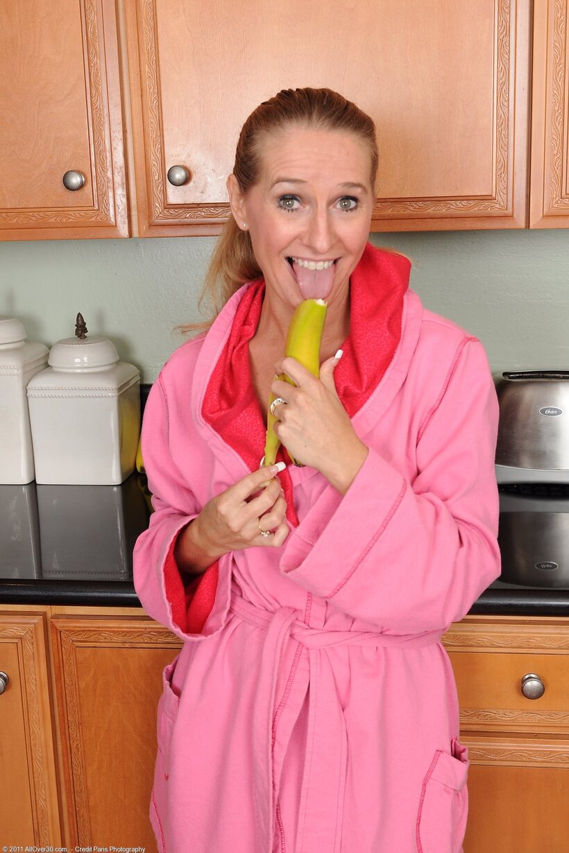 Photo 1 — Sara James eats a banana while stripping naked in the kitchen