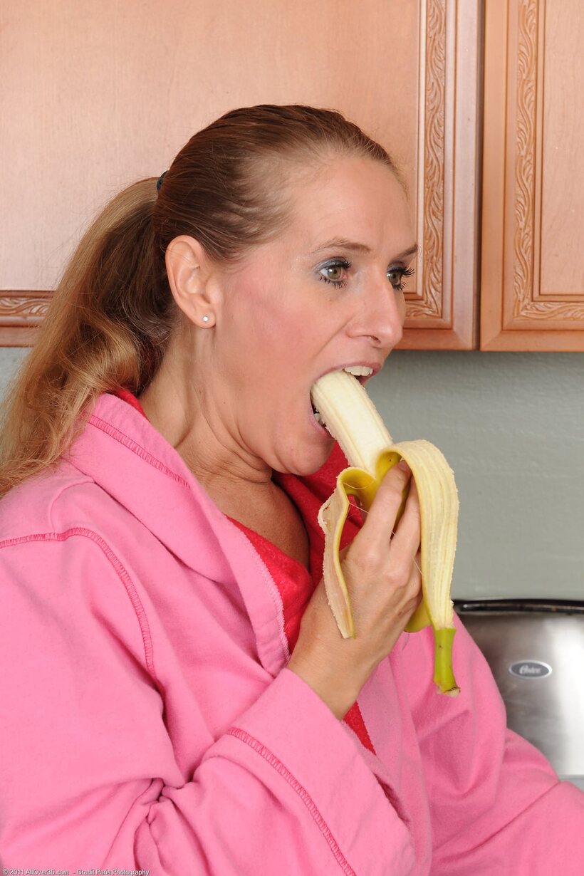 Sara James eats a banana while stripping naked in the kitchen (shot 3)