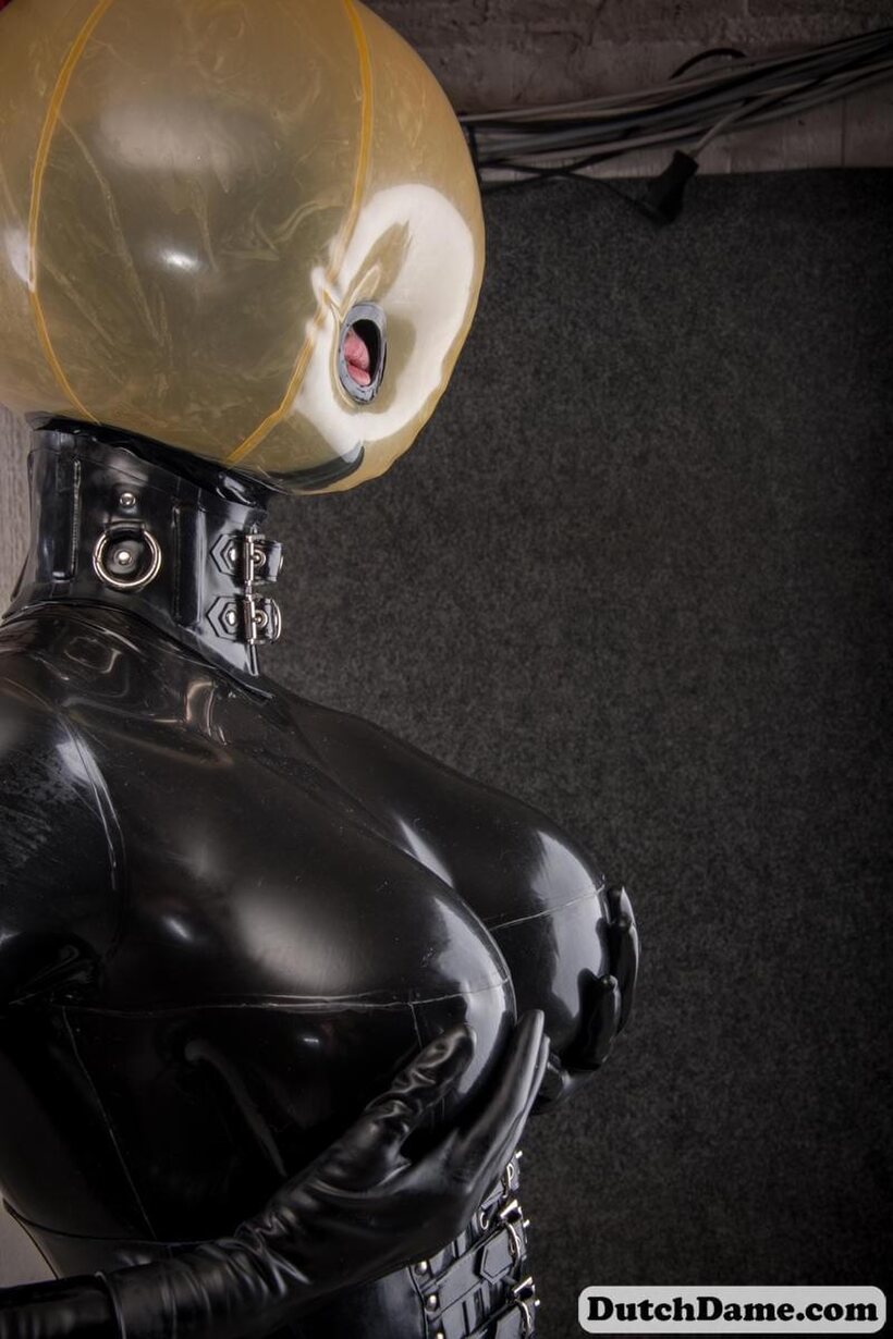 Latex slave gets strapped in and hooded inside the dungeon (shot 14)