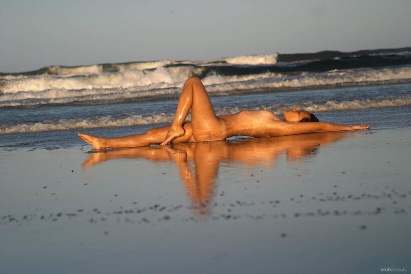 Image 3/21: Slim Asian babe stands naked in the surf during low tide