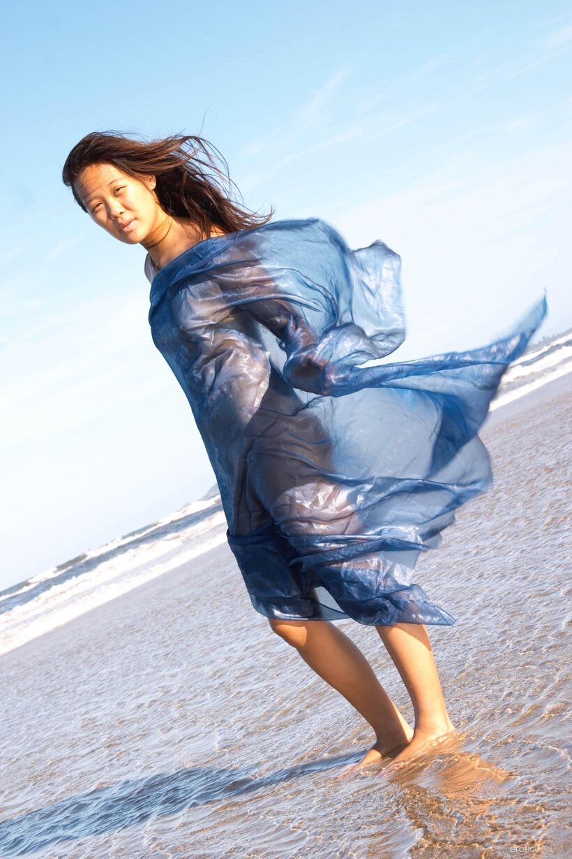Image 16/21: Slim Asian babe stands naked in the surf during low tide