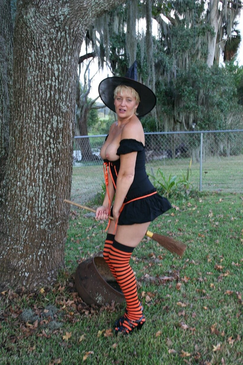 Image 10/20: Outdoors in a Halloween costume, Tracy Lick teases her ass with a broom