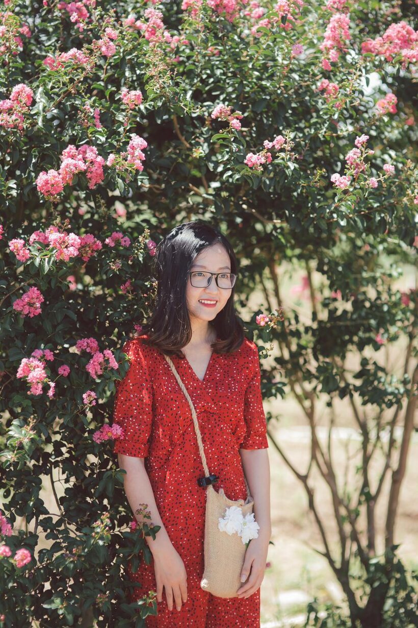 Image 6/21: Glasses on, an Asian babe poses outdoors in a red dress