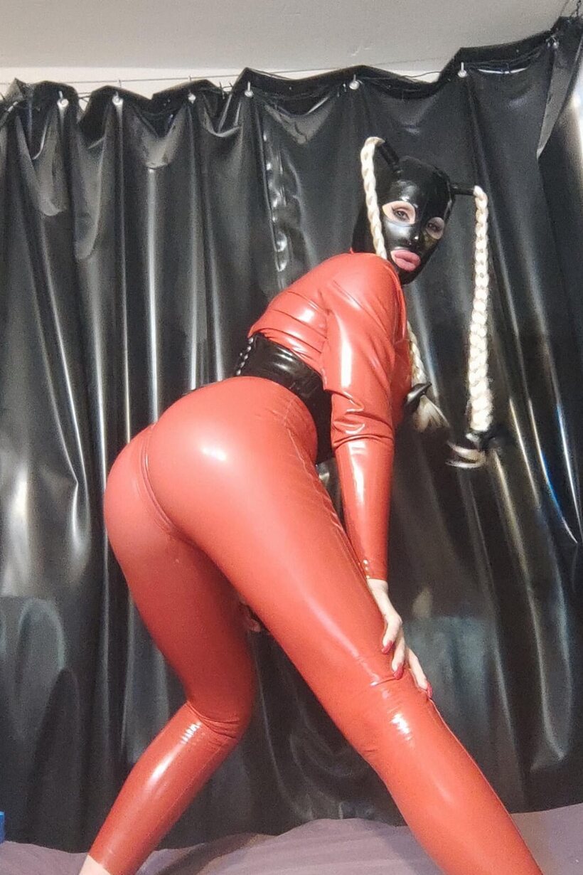 Image 7/16: Long braided pigtails frame her ass in tight latex