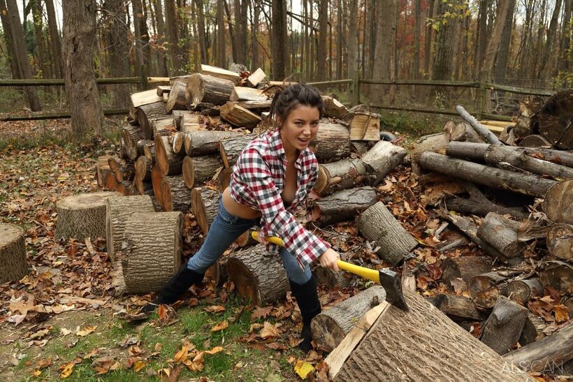Image 3/16: Daisy Haze strips down to boots while chopping wood outdoors