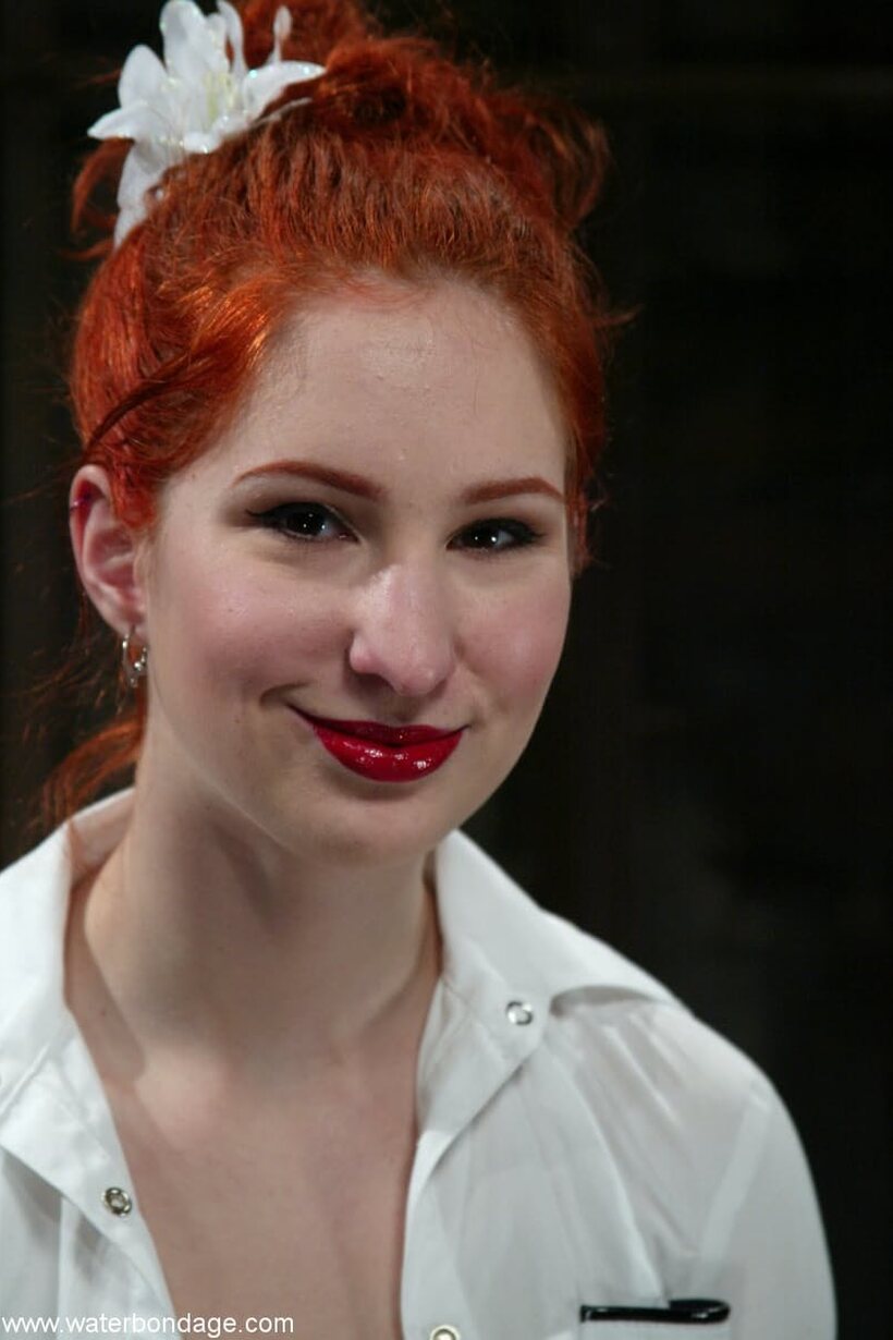 In the dungeon, a pale redhead is tied up and pleasured (shot 1)