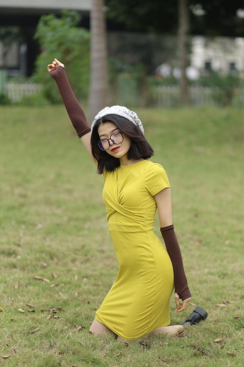 Image 4/21: Irena poses in a yellow dress and glasses, looking shy