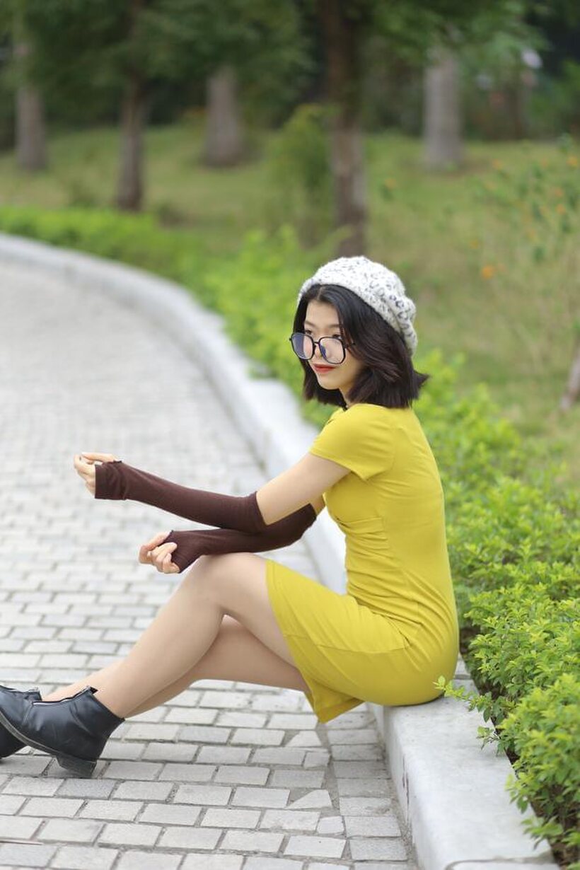 Image 16/21: Irena poses in a yellow dress and glasses, looking shy