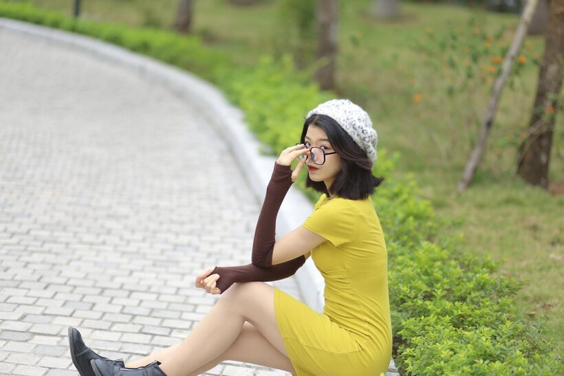 Image 17/21: Irena poses in a yellow dress and glasses, looking shy