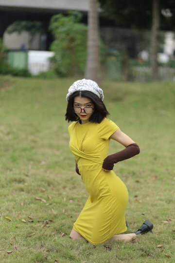 Irena poses in a yellow dress and glasses, looking shy