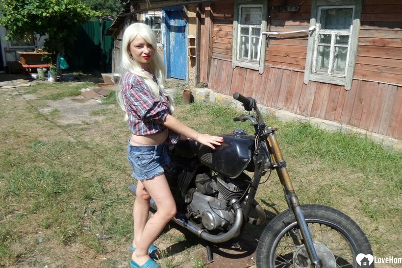 Blonde American poses on a motorbike, then strips to flash her booty (shot 1)