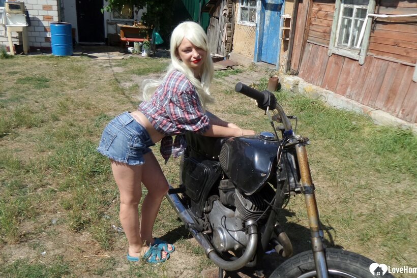 Photo 2 — Blonde American poses on a motorbike, then strips to flash her booty