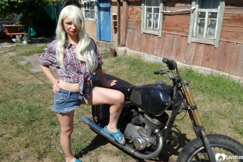 Blonde American poses on a motorbike, then strips to flash her booty (shot 3)