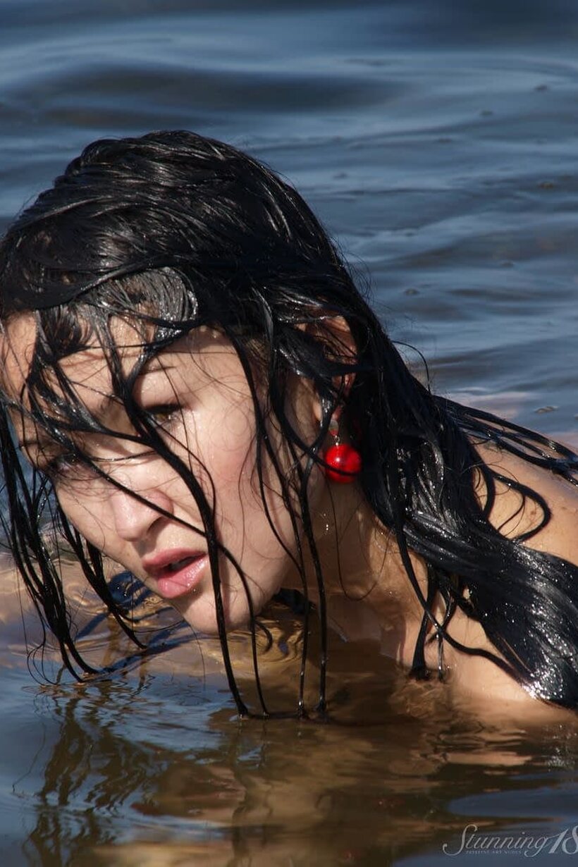 Photo 16 — At the beach, a young beauty strips her bikini off and poses nude in the ocean
