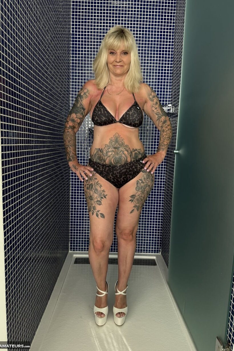 Tattooed blonde undresses in the shower wearing white heels (shot 1)