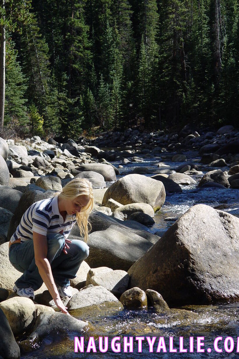 Naughty Allie strips naked on a boulder in the stream, blonde MILF style (shot 1)
