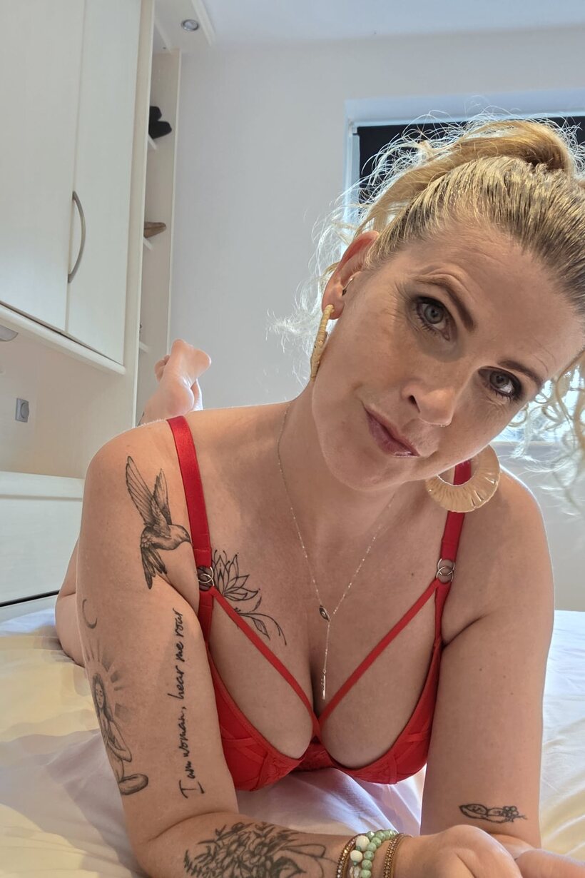 BBW nude photo 2 — Red lingerie and a pierced lip frame this tattooed BBW solo scene