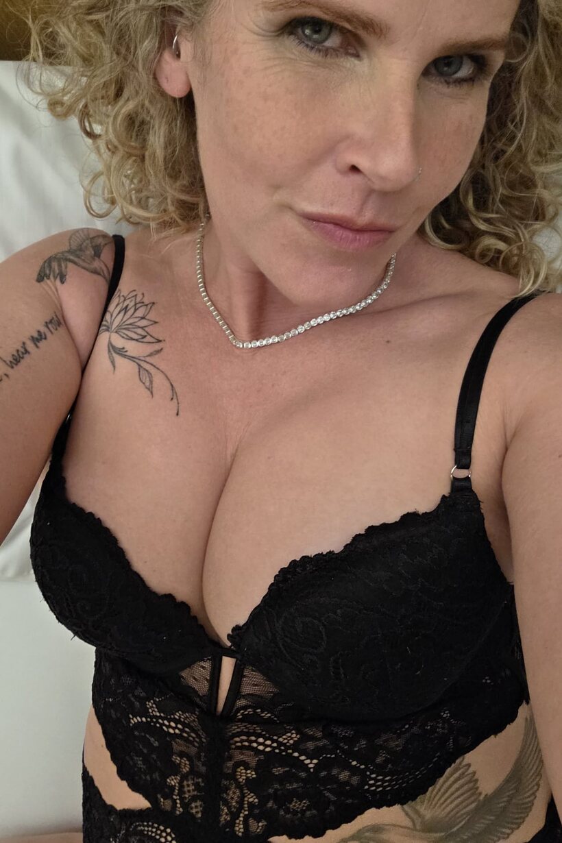 Curly-haired MILF models black lingerie while playing solo for the camera (shot 1)