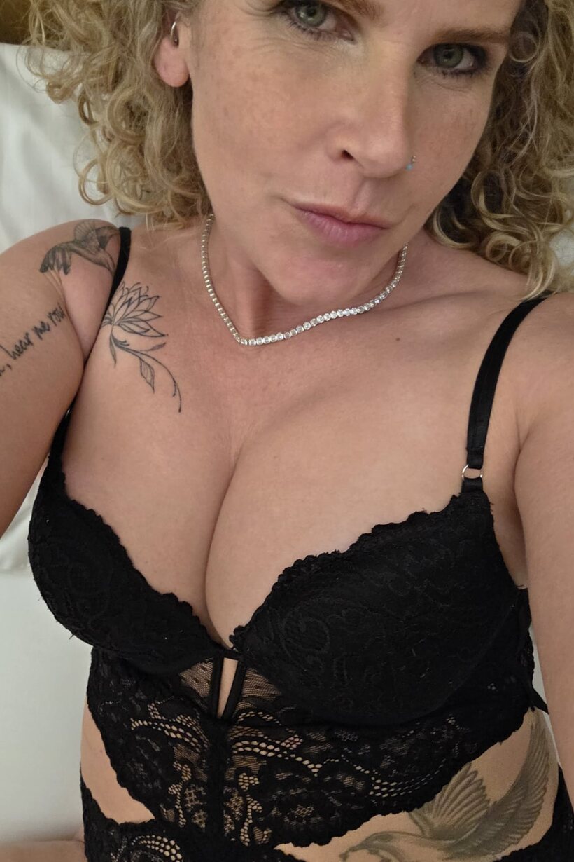Curly-haired MILF models black lingerie while playing solo for the camera (shot 9)